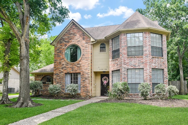 traditional-style home featuring central air condition unit, brick siding, a shingled roof, and a front yard