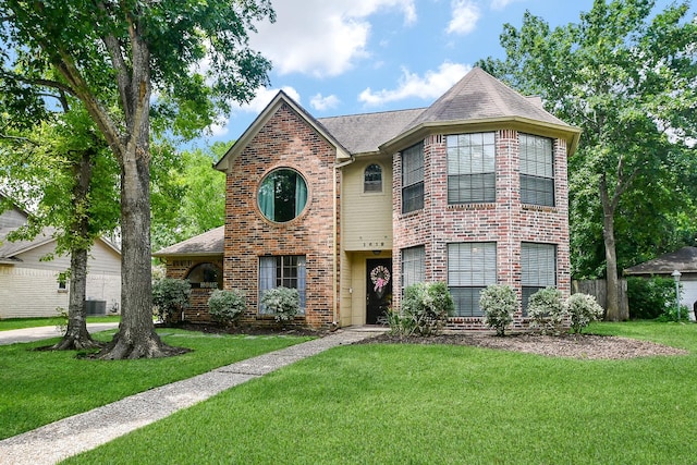 view of front facade with fence, a shingled roof, a front yard, and brick siding
