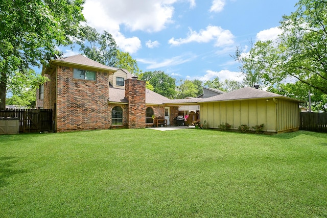 back of property featuring a fenced backyard, a chimney, brick siding, a patio area, and a yard