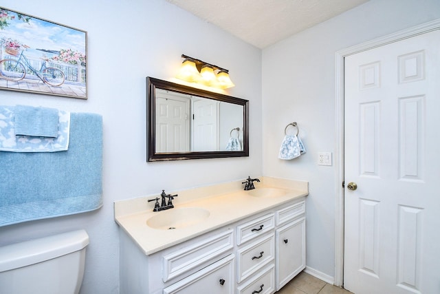 bathroom featuring double vanity, a sink, tile patterned flooring, and toilet