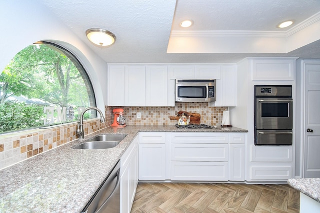 kitchen featuring white cabinetry, light stone counters, a sink, appliances with stainless steel finishes, and a warming drawer
