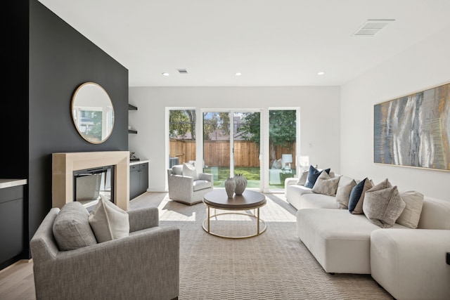 living area with visible vents, a glass covered fireplace, recessed lighting, and light wood-type flooring