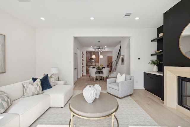 living area featuring stairway, an inviting chandelier, light wood finished floors, visible vents, and recessed lighting