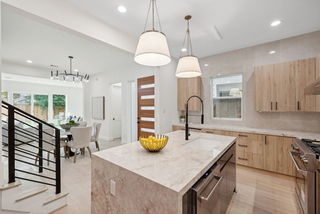 kitchen with light brown cabinets, modern cabinets, a center island with sink, appliances with stainless steel finishes, and light stone countertops