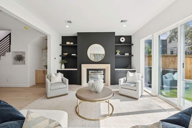 living room with stairway, visible vents, light wood finished floors, and built in shelves