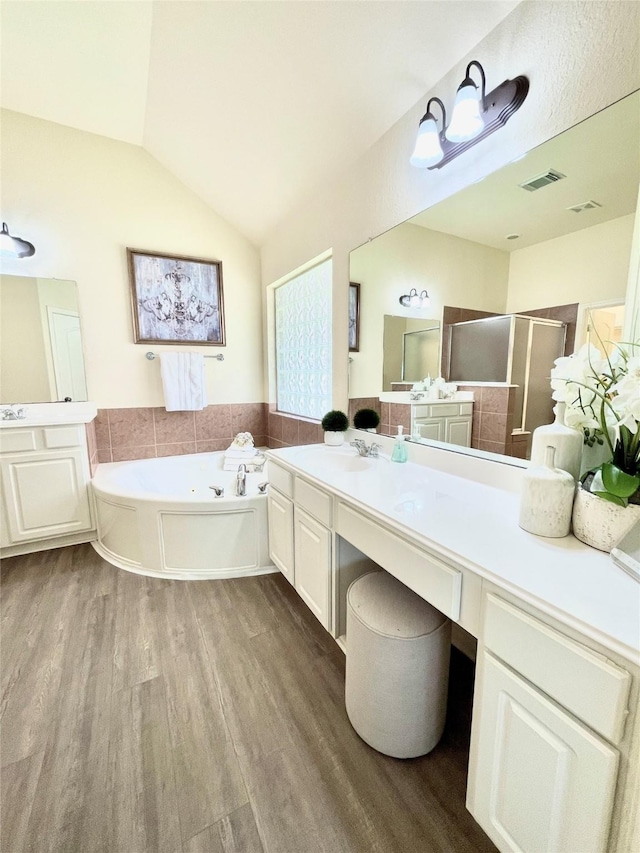 26936 Chateau Lake Dr, Kingwood, TX 77339 - bathroom featuring wood finished floors, vaulted ceiling, vanity, a bath, and a stall shower