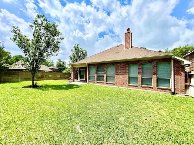 26936 Chateau Lake Dr, Kingwood, TX 77339 - back of property featuring a chimney, a fenced backyard, a yard, roof with shingles, and brick siding