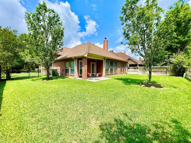 26936 Chateau Lake Dr, Kingwood, TX 77339 - back of house with a chimney, a fenced backyard, a patio area, a lawn, and brick siding