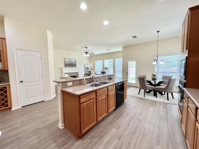 26936 Chateau Lake Dr, Kingwood, TX 77339 - kitchen featuring a sink, ceiling fan with notable chandelier, black appliances, light wood finished floors, and a fireplace