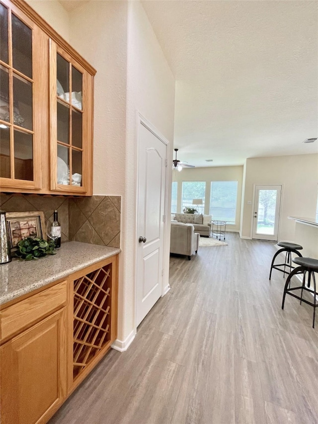 26936 Chateau Lake Dr, Kingwood, TX 77339 - bar featuring baseboards, light wood-style floors, ceiling fan, and tasteful backsplash