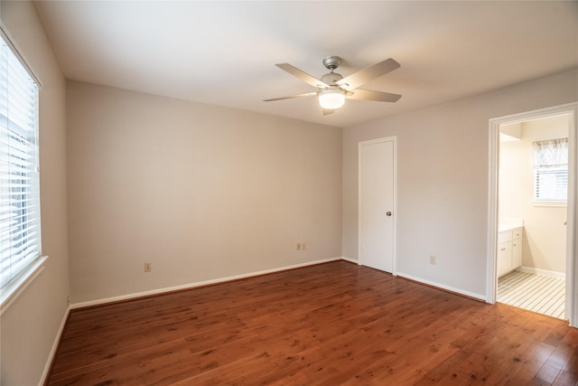 unfurnished bedroom with baseboards, wood finished floors, connected bathroom, and ceiling fan