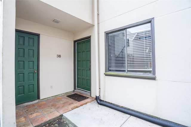 property entrance featuring visible vents and stucco siding