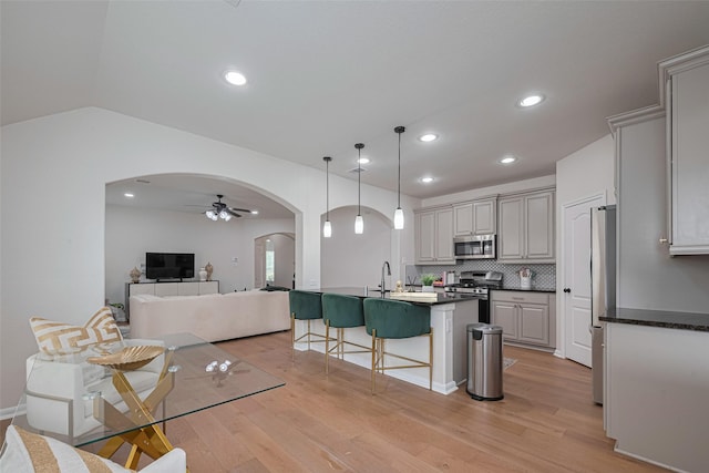 12205 Renewal Way, Houston, TX 77047 - kitchen featuring stainless steel appliances, arched walkways, a breakfast bar, dark countertops, and recessed lighting