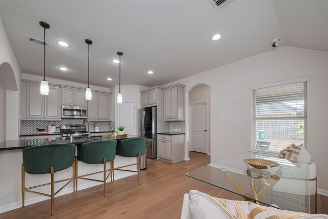 12205 Renewal Way, Houston, TX 77047 - kitchen with appliances with stainless steel finishes, arched walkways, dark countertops, a breakfast bar area, and light wood finished floors