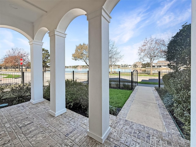 view of patio / terrace featuring a water view and fence