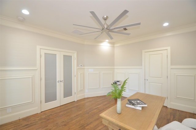 office space featuring ornamental molding, french doors, a ceiling fan, a decorative wall, and wood finished floors