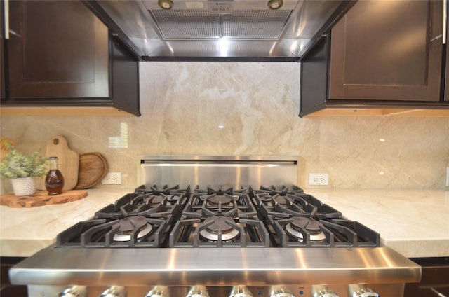 kitchen featuring gas range, dark brown cabinetry, tasteful backsplash, and ventilation hood