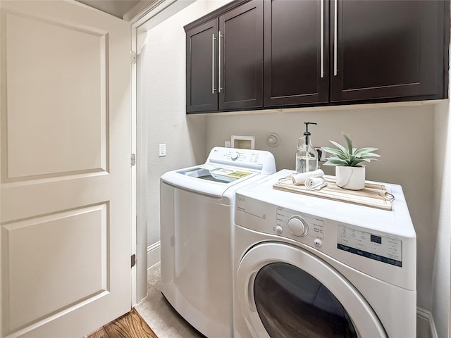 clothes washing area with washing machine and dryer, light wood-type flooring, and cabinet space