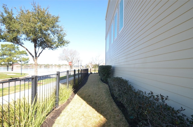 view of property exterior with a water view and fence