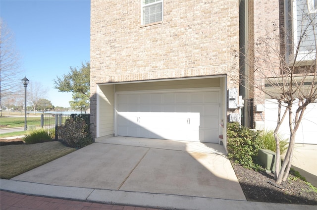 garage with fence and concrete driveway