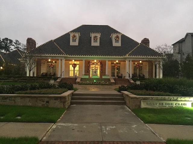 view of front facade featuring a chimney and covered porch