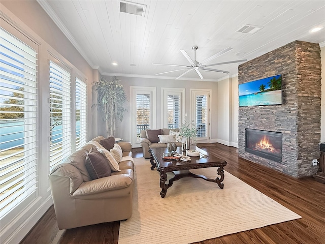 living room with wood finished floors, ceiling fan, a fireplace, and visible vents