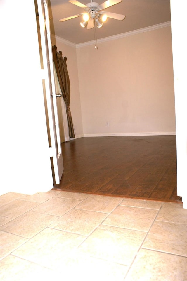 empty room with ornamental molding, a ceiling fan, light wood-style flooring, and baseboards