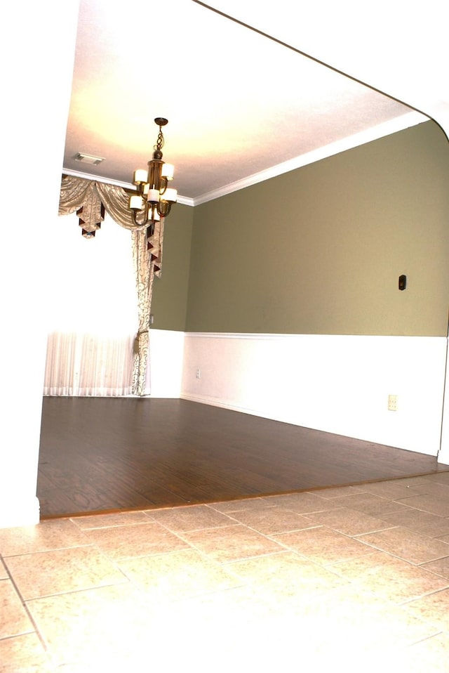 unfurnished room with a chandelier, crown molding, visible vents, and baseboards