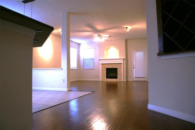 unfurnished living room featuring baseboards, wood finished floors, a ceiling fan, and a fireplace