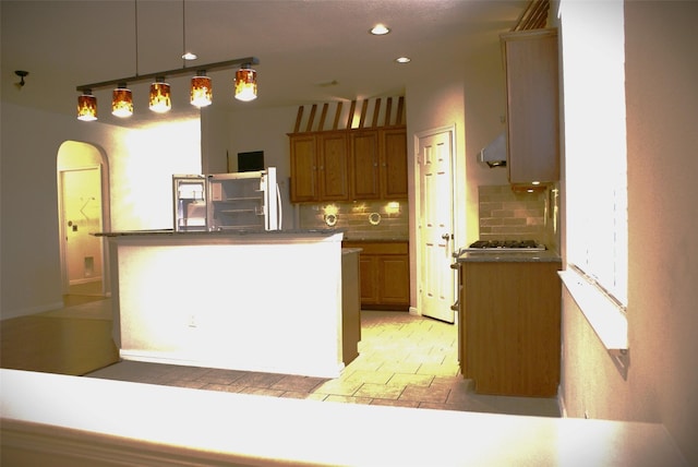 kitchen with recessed lighting, brown cabinetry, decorative light fixtures, backsplash, and a kitchen island