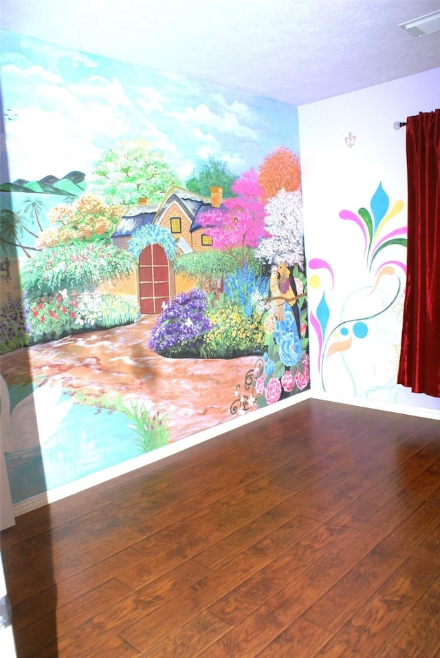 interior space with visible vents, hardwood / wood-style flooring, and baseboards