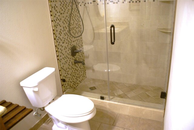 full bath featuring toilet, a shower stall, and tile patterned floors
