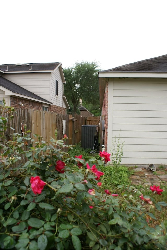 view of yard with central AC and fence