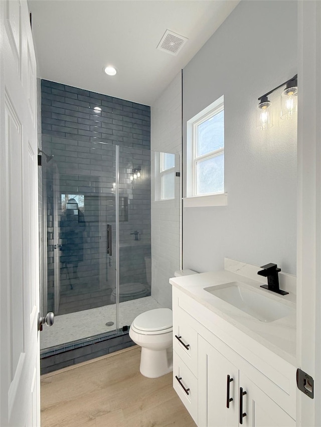 16366 Eastchase St, Montgomery, TX 77316 - bathroom with wood finished floors, visible vents, toilet, vanity, and a stall shower