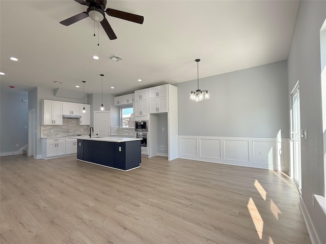 16366 Eastchase St, Montgomery, TX 77316 - kitchen with white cabinets, stainless steel appliances, ceiling fan with notable chandelier, decorative backsplash, and light countertops