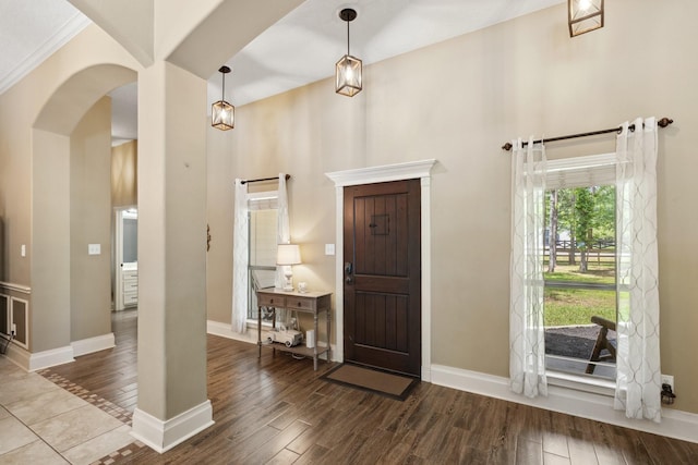 foyer featuring a towering ceiling, wood finished floors, baseboards, and arched walkways