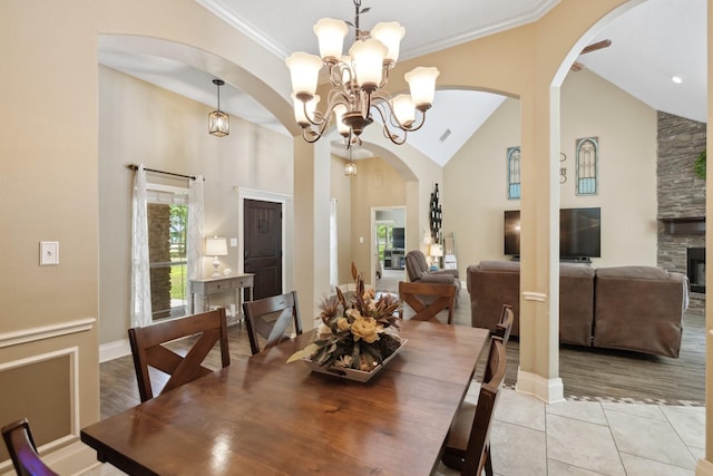 dining area with arched walkways, an inviting chandelier, high vaulted ceiling, and plenty of natural light
