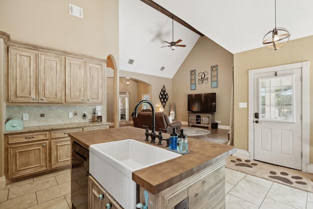 kitchen featuring light tile patterned flooring, arched walkways, a sink, and a ceiling fan