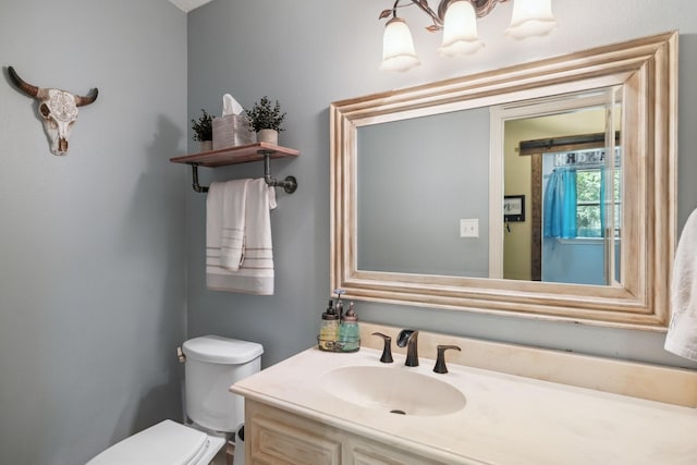 bathroom featuring an inviting chandelier, vanity, and toilet