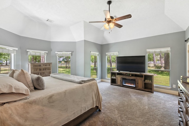 bedroom with visible vents, carpet flooring, high vaulted ceiling, and a glass covered fireplace