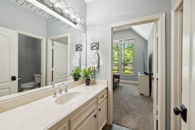 bathroom featuring toilet, vaulted ceiling, vanity, and baseboards
