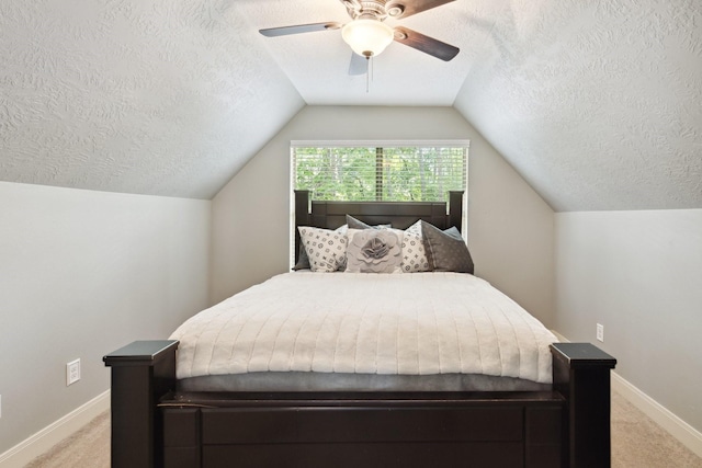 bedroom featuring ceiling fan, vaulted ceiling, baseboards, a textured ceiling, and light colored carpet