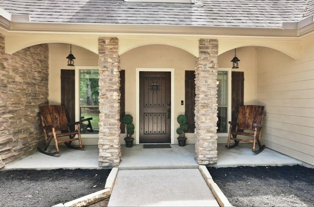 property entrance featuring a shingled roof and covered porch