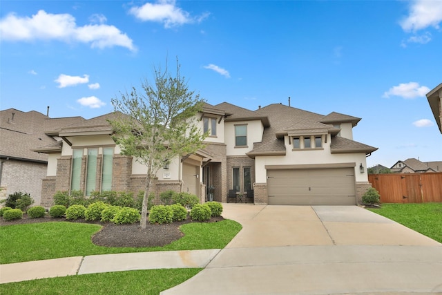 prairie-style house with a garage, brick siding, fence, concrete driveway, and stucco siding