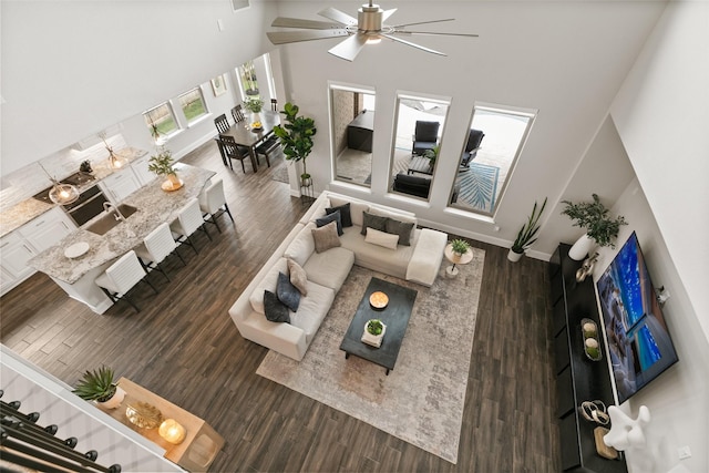 living room featuring baseboards, a towering ceiling, wood finished floors, and ceiling fan