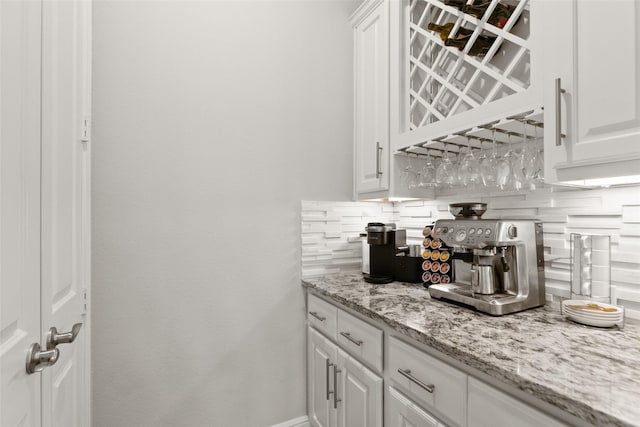bar with a bar, decorative backsplash, and baseboards