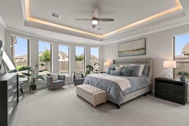 carpeted bedroom featuring a tray ceiling, visible vents, and ornamental molding