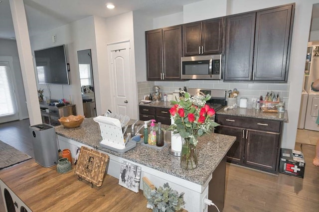 219 Lisa Marie Dr, Angleton, TX 77515 - kitchen featuring dark brown cabinets, light wood-type flooring, washing machine and dryer, appliances with stainless steel finishes, and light stone countertops