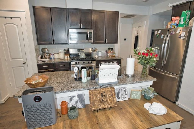 219 Lisa Marie Dr, Angleton, TX 77515 - kitchen with stainless steel appliances, backsplash, wood finished floors, light stone countertops, and dark brown cabinetry