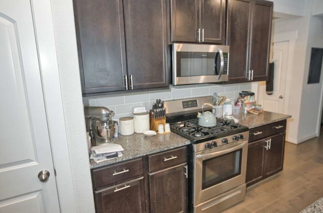 219 Lisa Marie Dr, Angleton, TX 77515 - kitchen featuring dark brown cabinets, stone countertops, backsplash, and appliances with stainless steel finishes